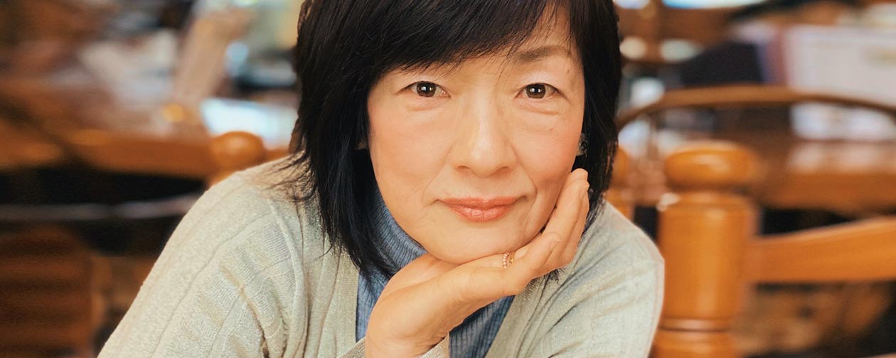 Portrait of a smiling middle-aged woman resting her chin on her hand, representing a confident investor.