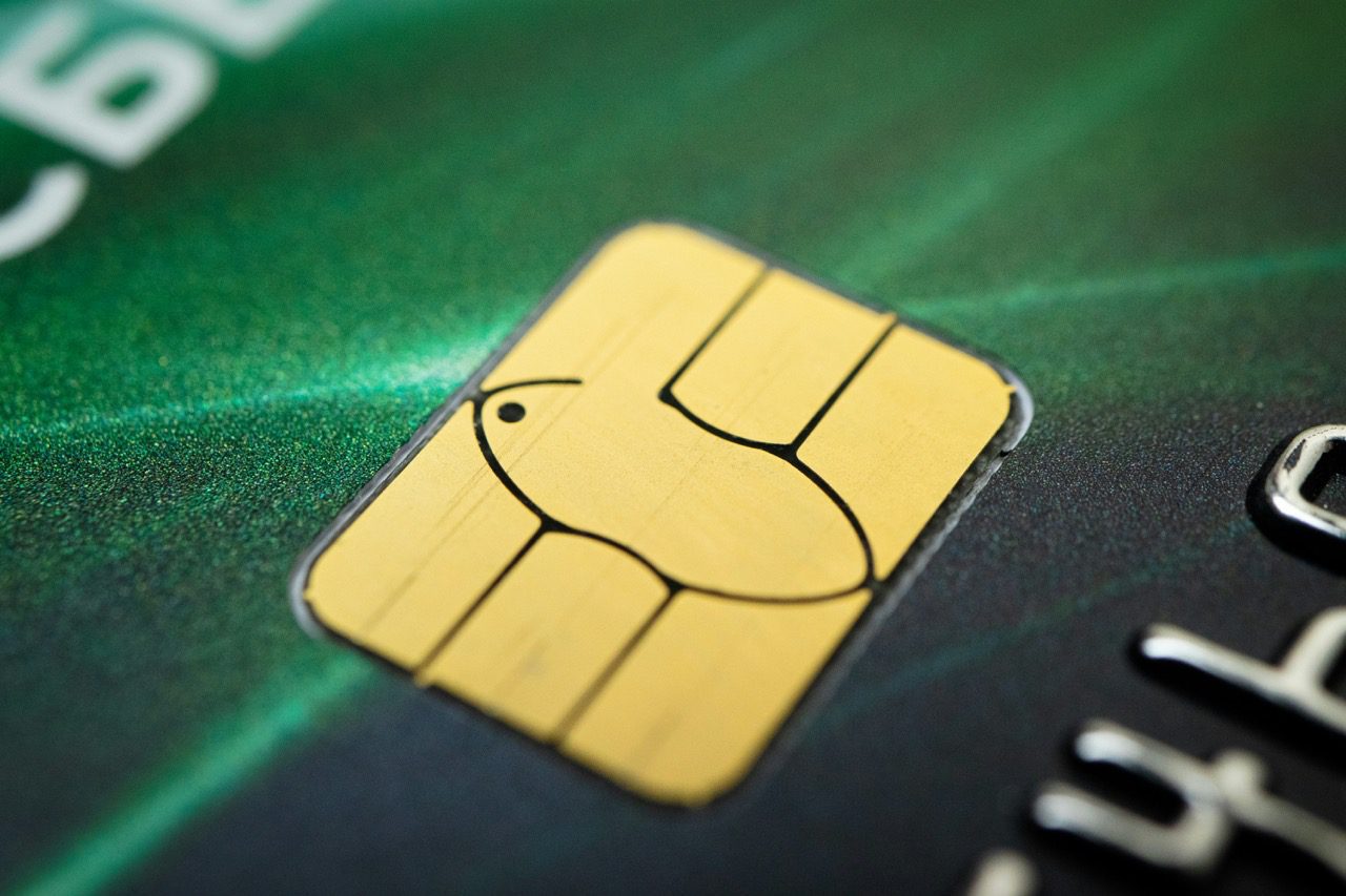 Extreme close-up of a gold EMV security chip on a green credit card.