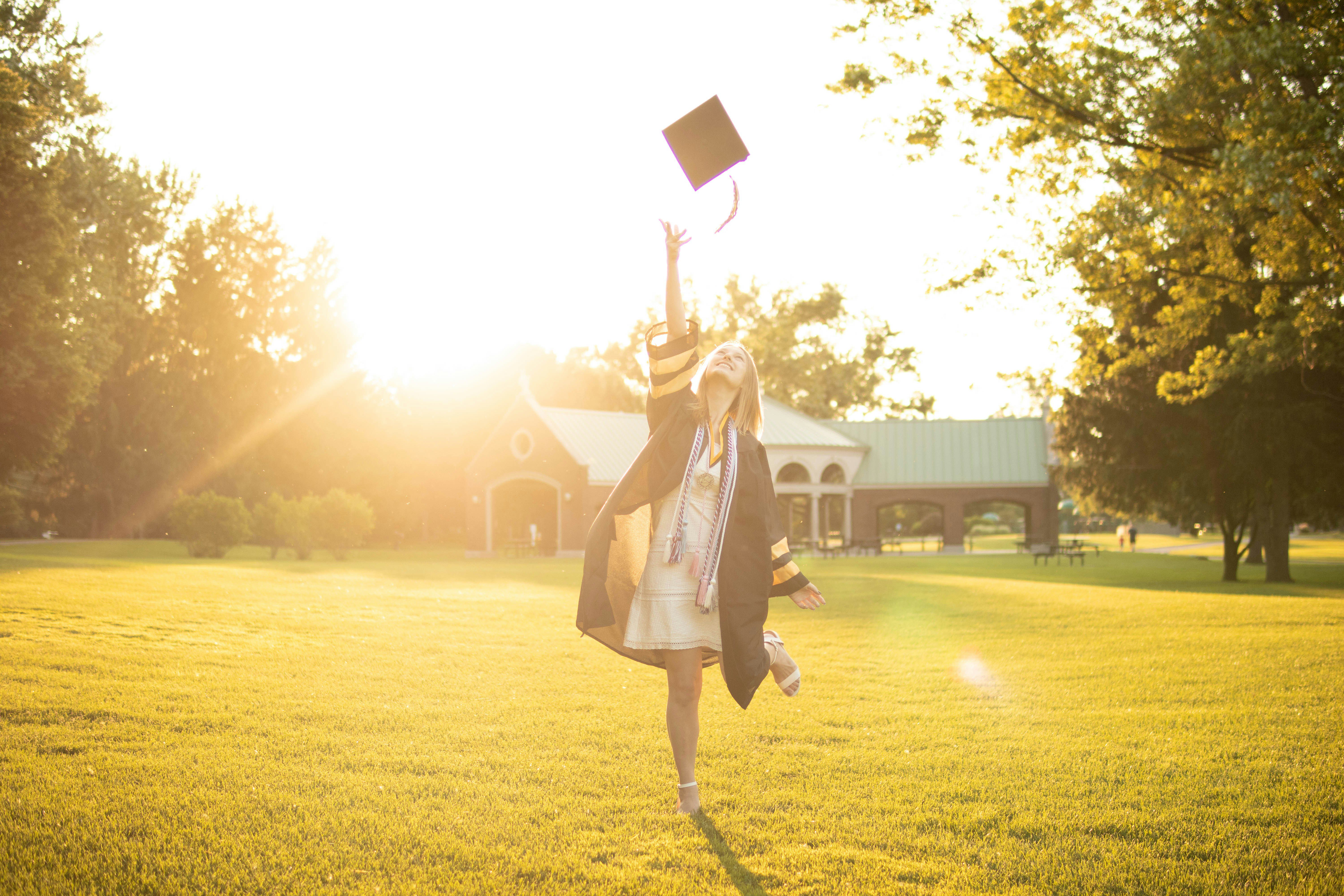 young woman throwing graduation cap into the air