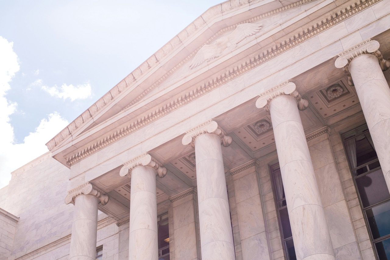 Low-angle view of a white marble government building with large classical columns and an eagle crest.