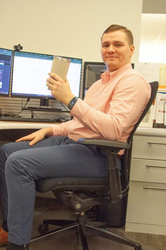 Marcus Wolf holding coffee at his Bridgewater Advisors desk